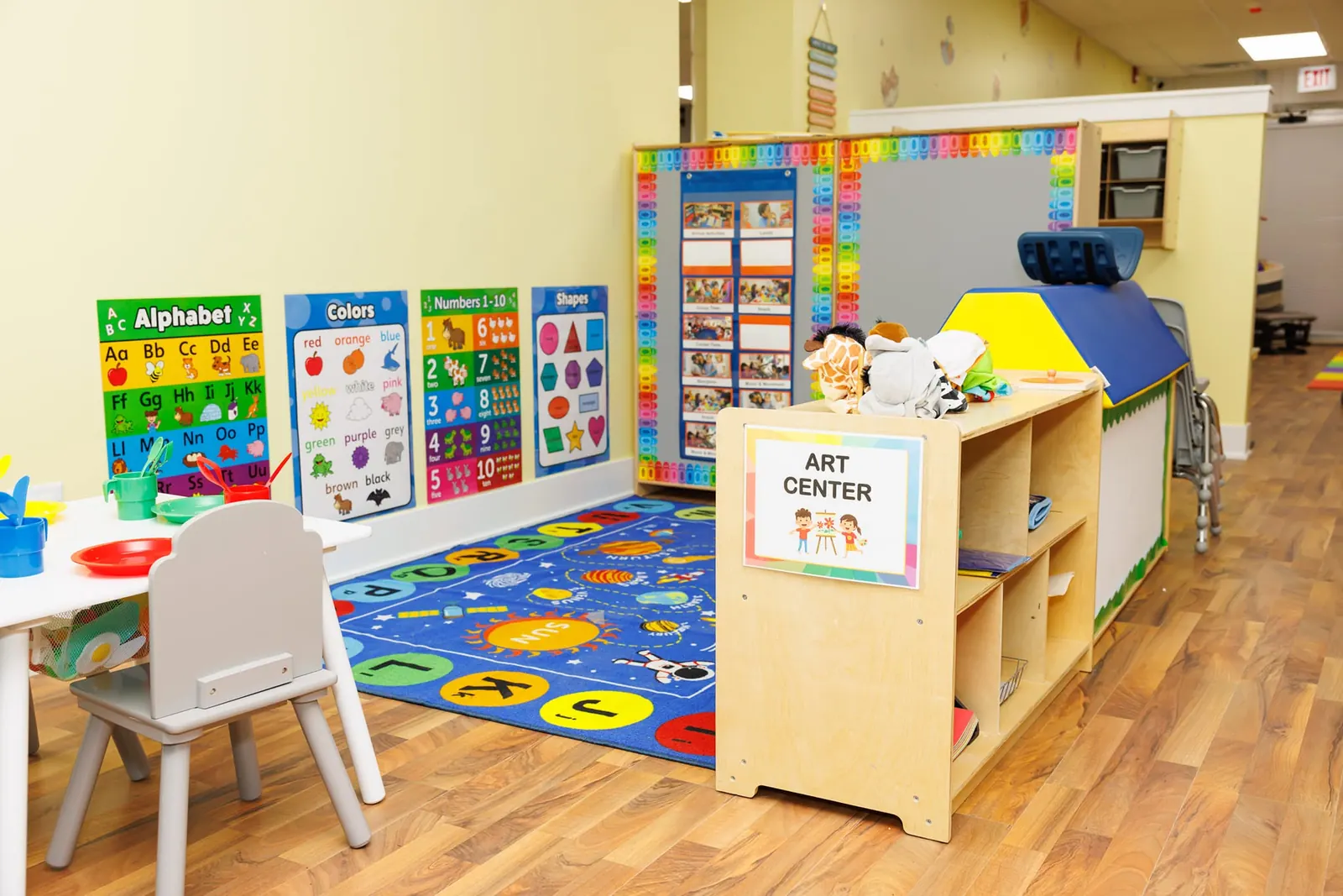 Art center with an alphabet rug, easel and supply shelves
