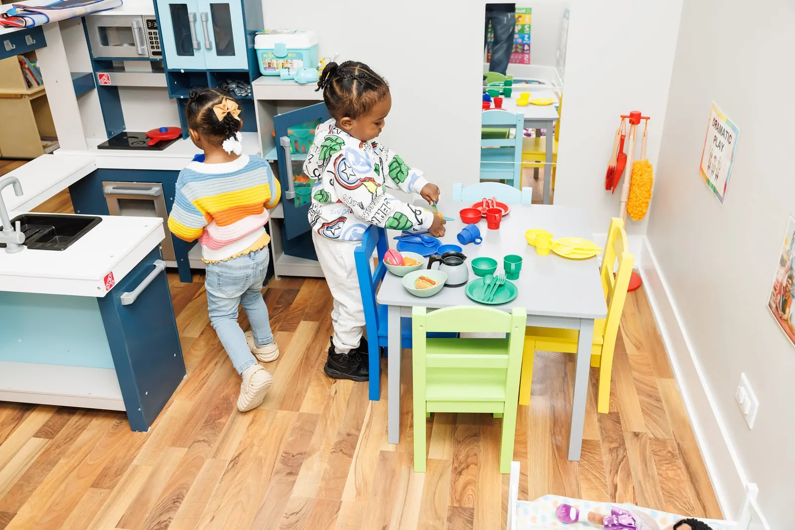 Two young children playing together in a pretend kitchen